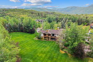 View from above of property featuring a mountainous background and a heavily wooded area