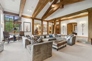 Carpeted living area featuring arched walkways, beamed ceiling, and high vaulted ceiling