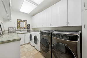 Washroom with cabinet space, independent washer and dryer, and light stone finish floors