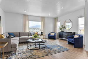Living room with wood finished floors, a textured ceiling, and recessed lighting