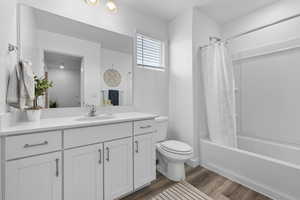 Full bath with vanity, shower / bath combination with curtain, and wood finished floors