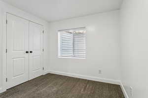 Unfurnished bedroom featuring dark colored carpet and a closet