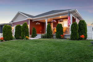 View of front facade with an attached garage, stone siding, and covered porch