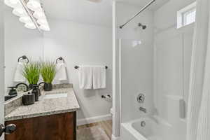 Bathroom featuring vanity, shower / bathtub combination with curtain, a chandelier, and wood finished floors