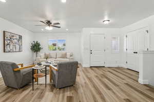 Living room with ceiling fan, light wood-style floors, and recessed lighting