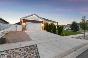 View of front of house with a gate, a garage, driveway, and stone siding