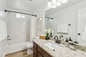 Full bathroom with wood finished floors, vanity, shower / bath combo with shower curtain, and a chandelier