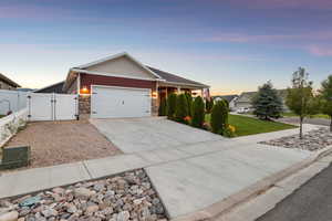 Craftsman-style house with a gate, a garage, driveway, and stone siding