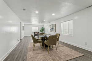 Dining room with a textured ceiling, dark wood-style flooring, and recessed lighting