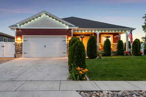 View of front facade featuring concrete driveway, a garage, stone siding, a gate, and covered porch