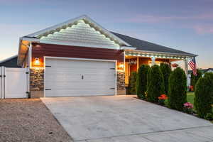 View of front of home featuring stone siding, driveway, an attached garage, and a gate