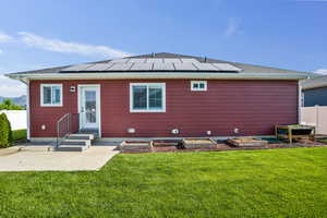 Rear view of property with roof mounted solar panels and a garden
