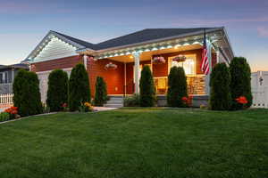 View of front of house featuring an attached garage, covered porch, and stone siding