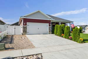 Craftsman inspired home with a gate, stone siding, an attached garage, and driveway