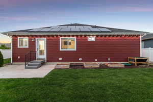 Back of house featuring solar panels, a patio, and a shingled roof