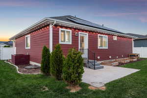 Rear view of house with roof mounted solar panels and a patio