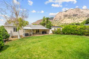 Rear view of house with a lawn, a mountain view, and a patio area