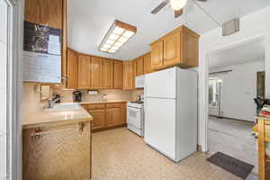 Kitchen with white appliances, light countertops, a ceiling fan, light floors, and decorative backsplash