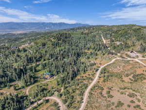 Aerial view of property's location with a mountainous background and a heavily wooded area
