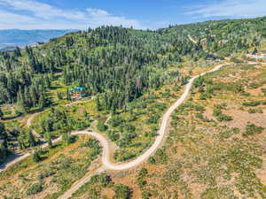 Aerial view of property and surrounding area with a forest and mountains