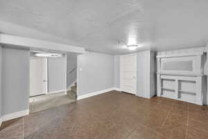 Finished basement featuring stairway and a textured ceiling