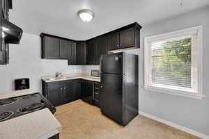 Kitchen with black appliances, healthy amount of natural light, light countertops, and ventilation hood