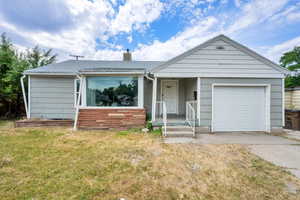 Ranch-style home with concrete driveway, an attached garage, a front lawn, a shingled roof, and a chimney