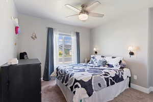 Carpeted bedroom featuring a ceiling fan and baseboards