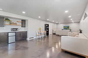 Living area with finished concrete flooring, recessed lighting, and wet bar