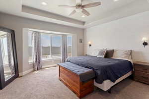 Bedroom featuring multiple windows, carpet flooring, recessed lighting, a tray ceiling, and ceiling fan