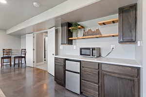 Kitchen with stainless steel appliances, open shelves, light countertops, and dark brown cabinets
