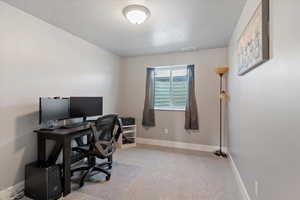 Office space with light colored carpet and a textured ceiling