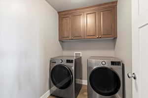 Laundry room featuring independent washer and dryer and cabinet space