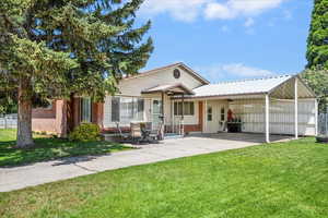 Rear view of house featuring concrete driveway, an attached carport, a yard, and brick siding
