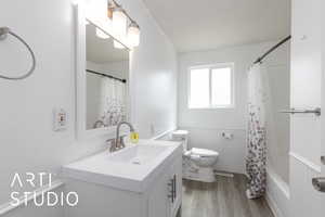 Bathroom featuring wood finished floors, vanity, a wainscoted wall, and shower / tub combo