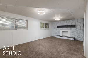 Unfurnished living room with carpet, a stone fireplace, and wooden walls