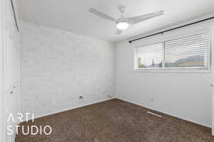Carpeted spare room featuring wallpapered walls and a ceiling fan