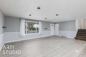Unfurnished room with a wainscoted wall, wood finished floors, and stairs