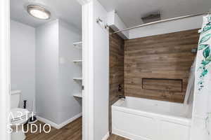 Bathroom with shower / bath combination with curtain, wood finished floors, and a textured ceiling