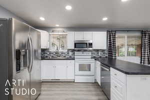 Kitchen with appliances with stainless steel finishes, a peninsula, healthy amount of natural light, dark countertops, and recessed lighting