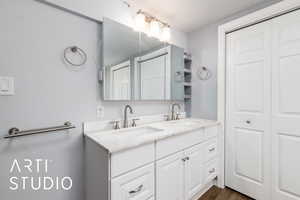 Bathroom with a closet, double vanity, and wood finished floors
