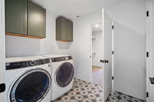 Washroom featuring cabinet space, washing machine and clothes dryer, and light floors