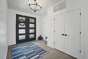 Entrance foyer with a chandelier, wood finished floors, and french doors