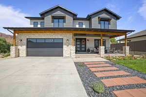 Contemporary home featuring stone siding, driveway, an attached garage, and a porch
