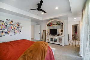Carpeted bedroom featuring recessed lighting, a raised ceiling, and ceiling fan