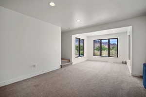 Empty room featuring carpet flooring, stairs, and recessed lighting