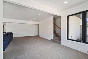 Unfurnished living room with recessed lighting, carpet floors, and stairway