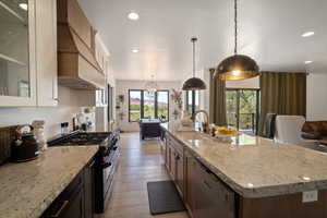 Kitchen with gas stove, premium range hood, dishwashing machine, light wood finished floors, and recessed lighting