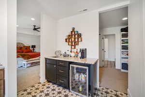 Indoor dry bar with wine cooler, light colored carpet, light floors, a ceiling fan, and recessed lighting