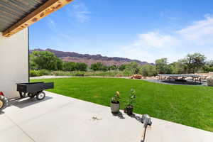 View of grassy yard with a mountain view and a patio